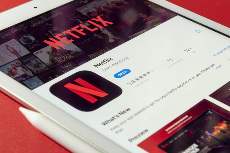 Aplikacja Netflix otwarta na tablecie leżącym na czerwonym stole