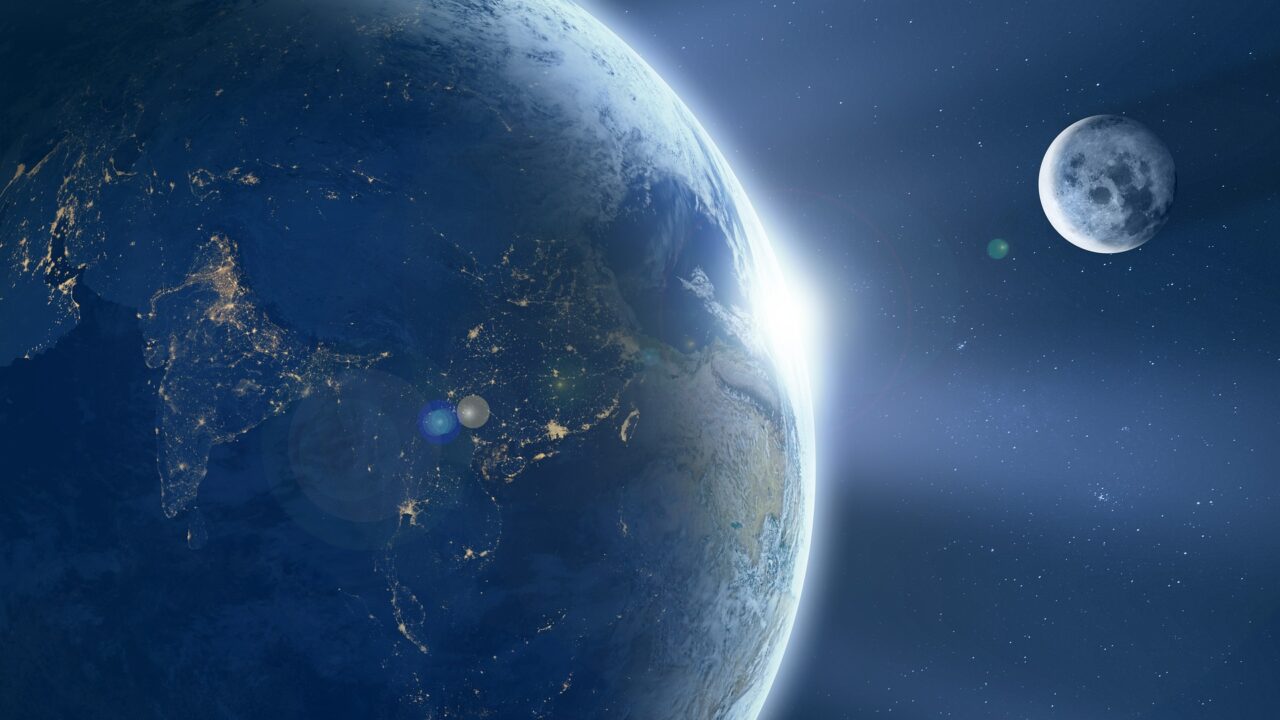 Widok Ziemi z kosmosu, gdzie widać oświetloną część świata z kontynentami Azją i Australią oraz Księżyc w tle.