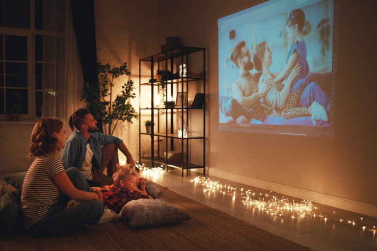 para siedząca na podłodze i oglądająca film wyświetlany przez projektor na ścianie