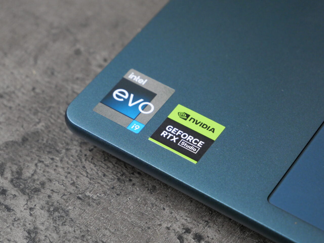 Narożnik niebieskiego laptopa z naklejkami 'Intel Evo i9' oraz 'Nvidia GeForce RTX Studio'.