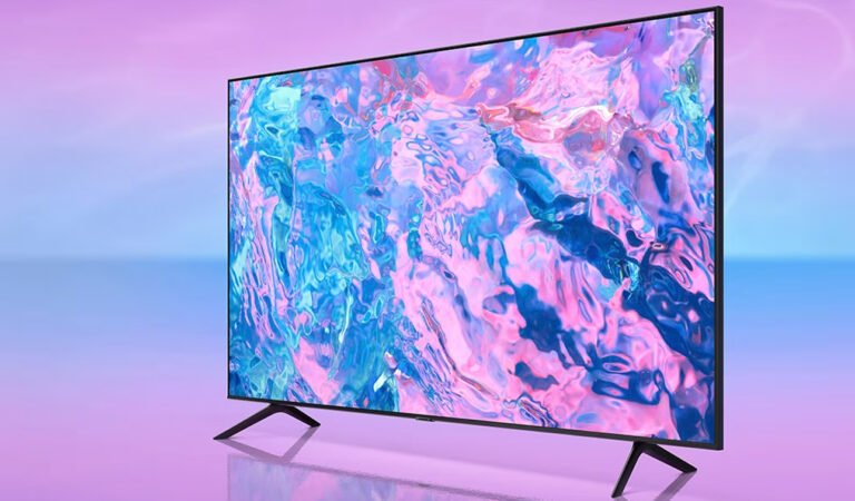 Nowoczesny telewizor smart TV Samsunga z płaskim ekranem wyświetlający abstrakcyjną grafikę w odcieniach różu i błękitu, na jednolitym tle o gradientowych barwach od różowego do błękitu.
