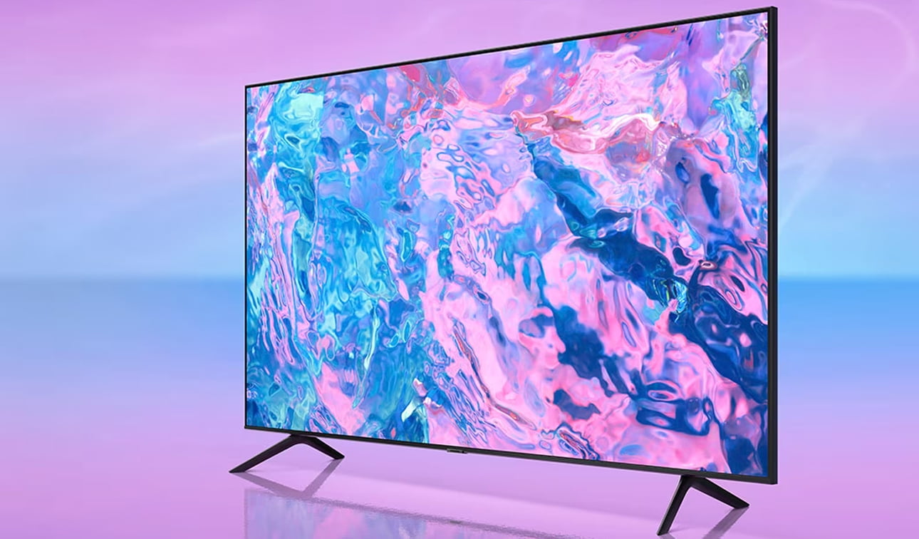 Nowoczesny telewizor smart TV Samsunga z płaskim ekranem wyświetlający abstrakcyjną grafikę w odcieniach różu i błękitu, na jednolitym tle o gradientowych barwach od różowego do błękitu.