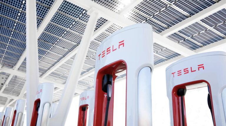 Stacja ładowania samochodów elektrycznych marki Tesla z dachem pokrytym panelami słonecznymi.
