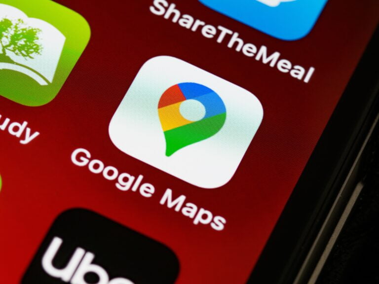 Ikona aplikacji Google Maps na ekranie smartfona z widocznymi ikonami innych aplikacji w tle.