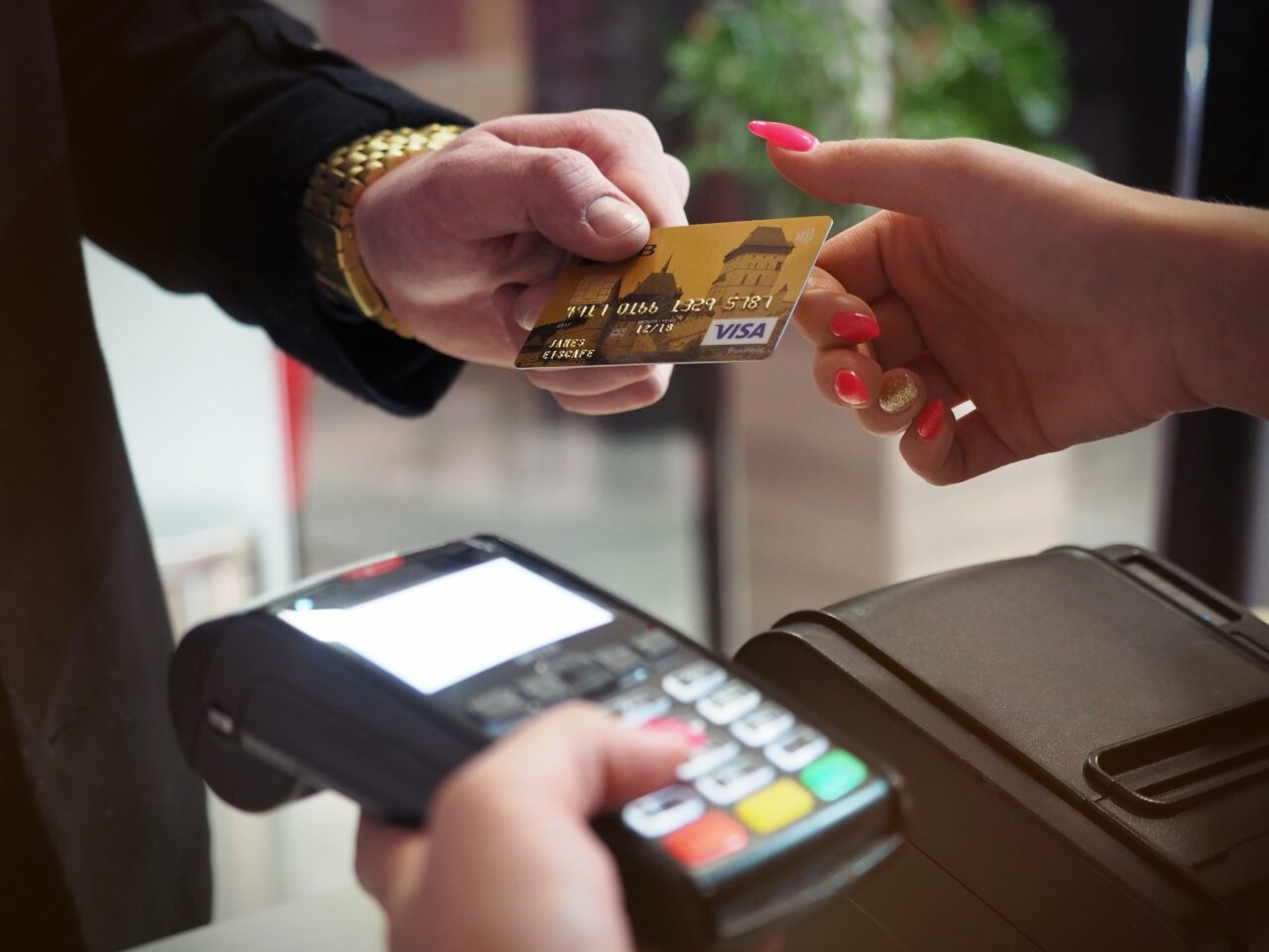 Osoba przekazuje kartę kredytową na terminal płatniczy do wykonania płatności.