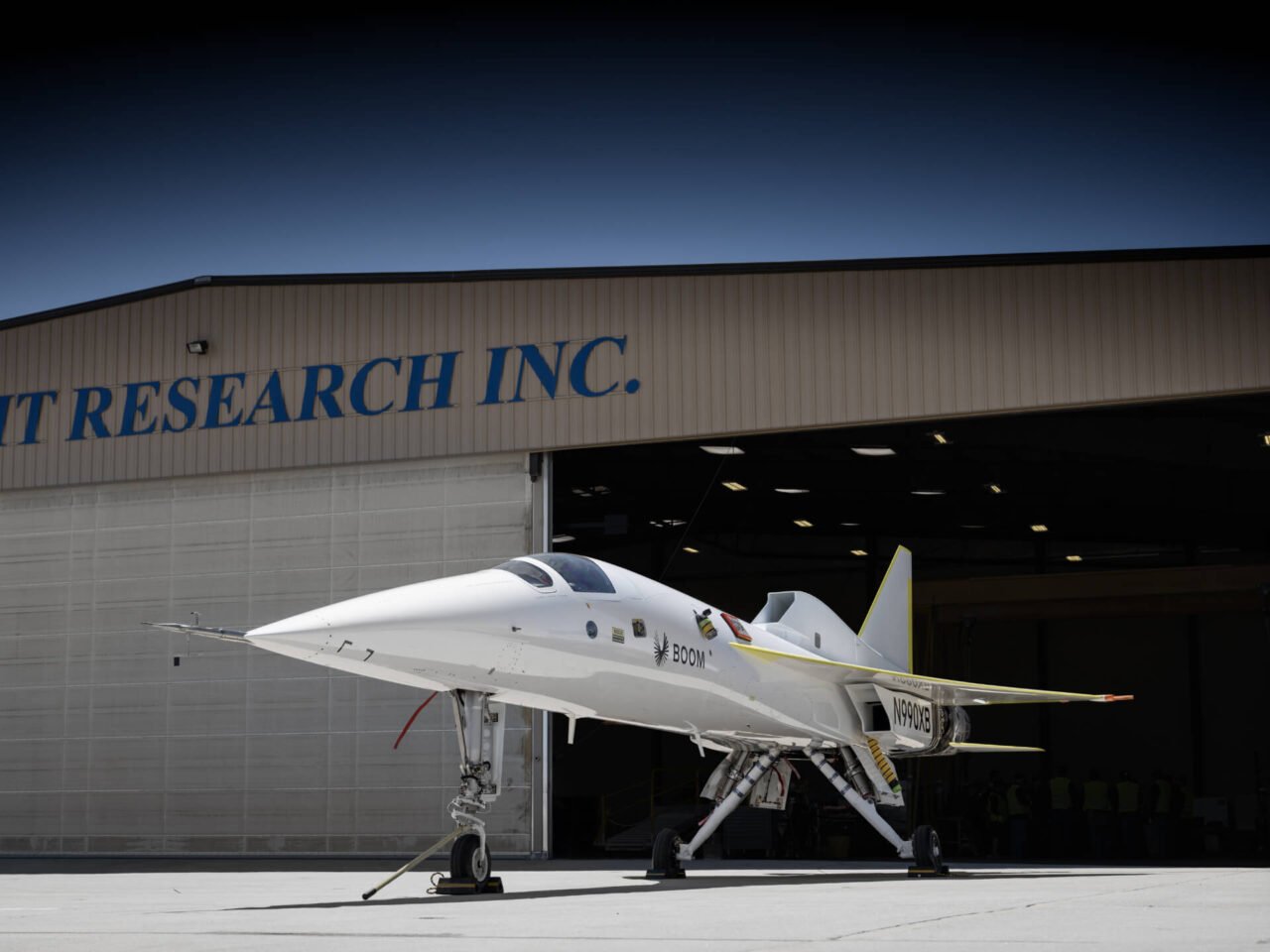 Naddźwiękowy odrzutowiec. Biały odrzutowiec badawczy przed hangarem z napisem "Flight Research Inc."