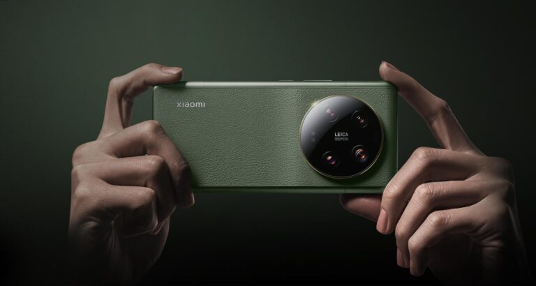 Zielony smartfon Xiaomi 14 z potrójnym aparatem fotograficznym Leica trzymany dwiema rękami na ciemnozielonym tle.