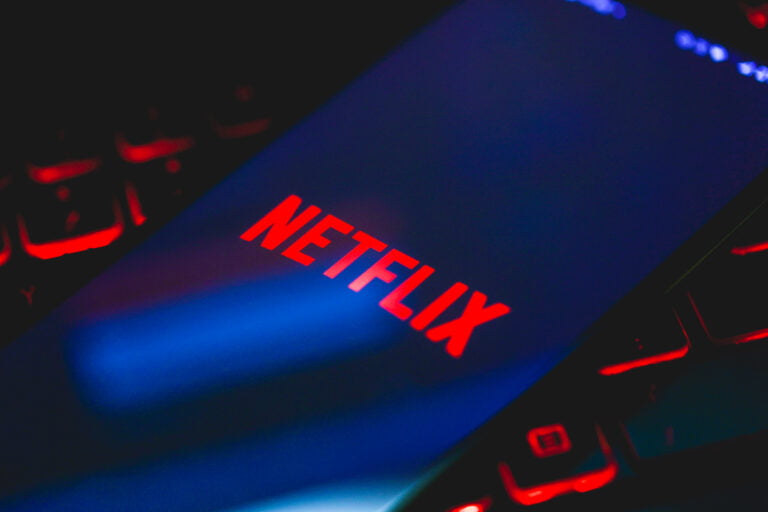 Logo Netflix na smartfonie leżącym na podświetlanej klawiaturze