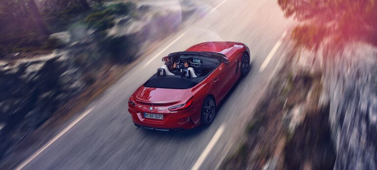 Czerwone sportowe BMW kabriolet na pustej drodze sfotografowane od tyłu.