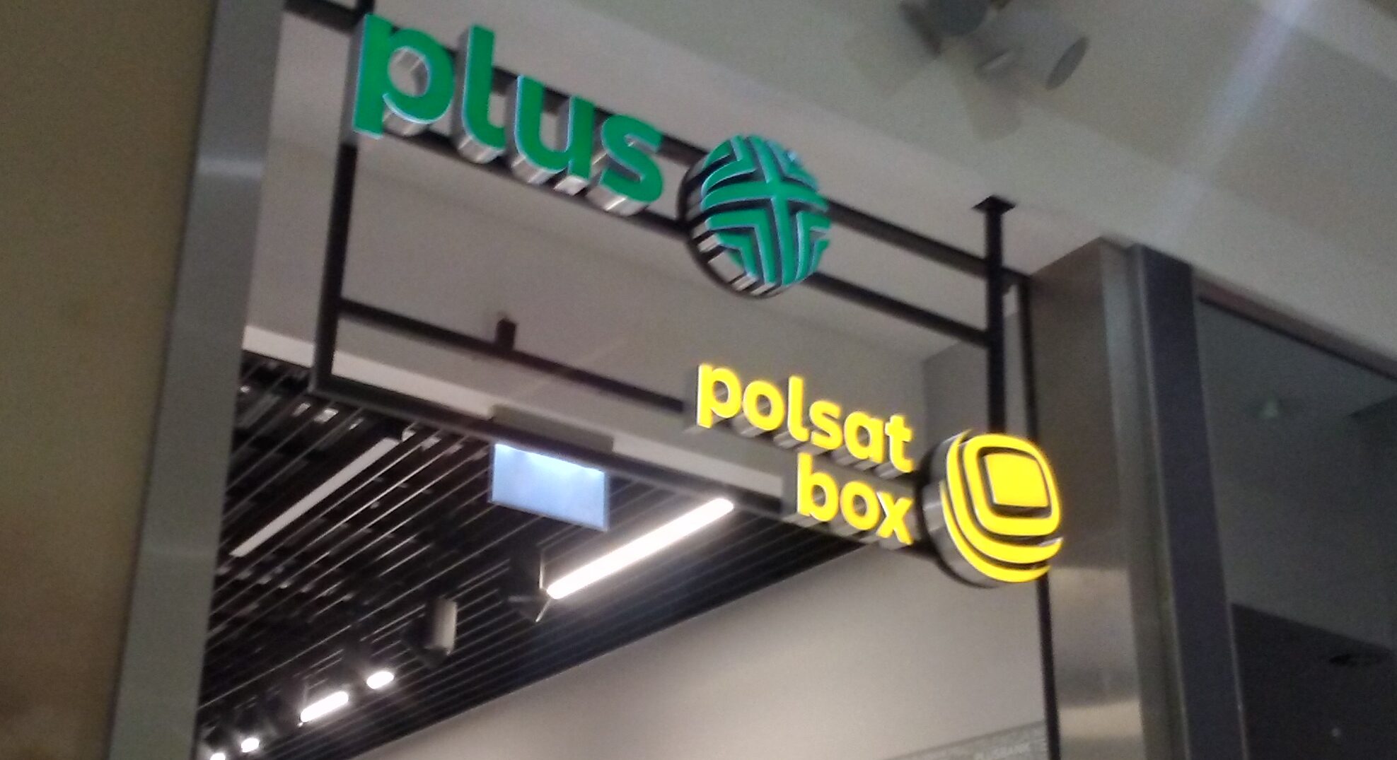 Logotypy sieci Plus i Polsat Box przed wejściem do sklepu