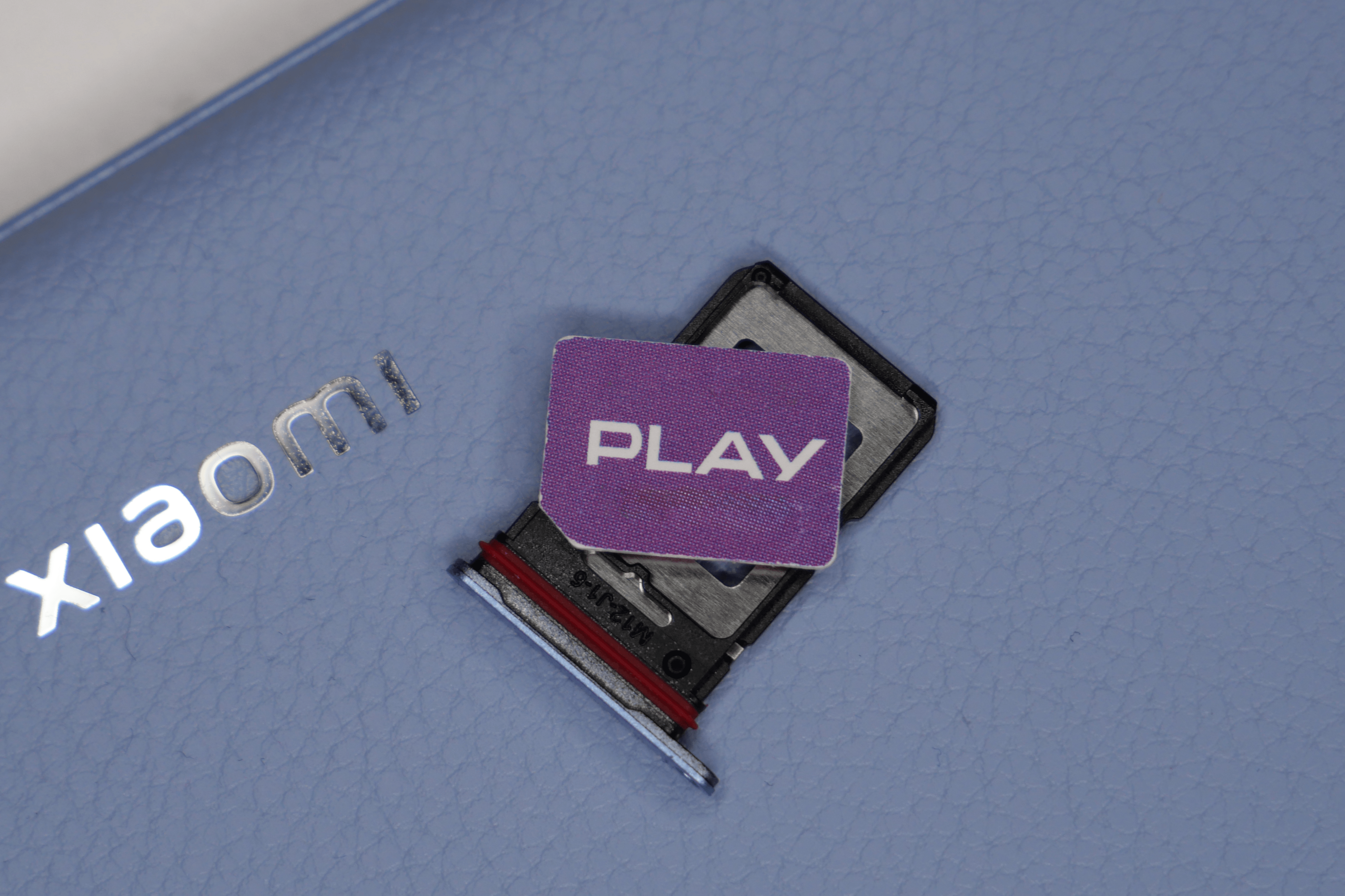 Karta nano SIM Play na tacce leżące na tylnej części smartfona Xiaomi 13T Pro