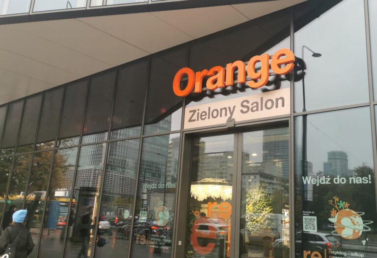 salon Orange z przeszklonymi drzwiami, nad wejściem pomarańczowy napis Orange, pod nim napis Zielony Salon