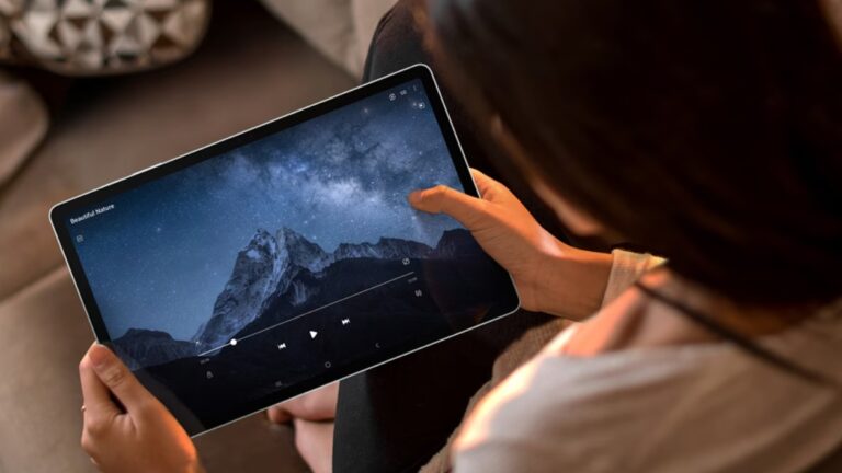 Osoba trzymająca tablet wyświetlający zdjęcie górskiego krajobrazu nocą pod gwiaździstym niebem.