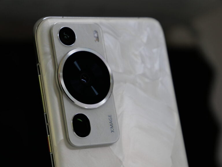 Zbliżenie na tylny aparat fotograficzny smartfona HUAWEI P60 Pro, z dużym okrągłym obiektywem i mniejszymi soczewkami, znajdujące się na błyszczącej, białej obudowie z napisem "X IMAGE".