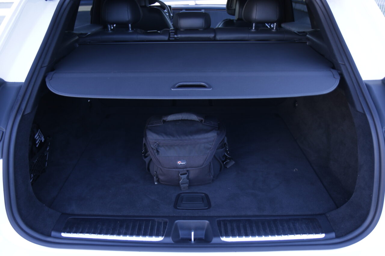 Otwarty bagażnik testowanego Mercedesa EQE SUV 350 4MATIC z zasłoniętą roletą i torbą na parat