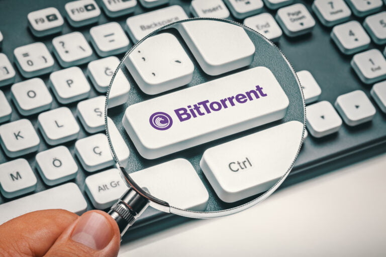 Biała klawiatura z logiem BitTorrent powiększonym za pomocą lupy