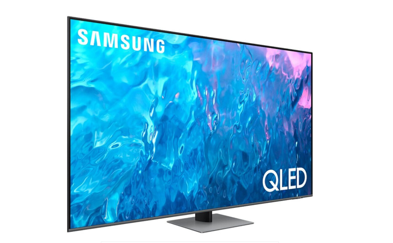 Telewizor Samsung QLED o płaskim ekranie wyświetlający dynamiczny obraz przypominający abstrakcyjną wodę w odcieniach niebieskiego i różu, z widocznym logo marki i technologii QLED.