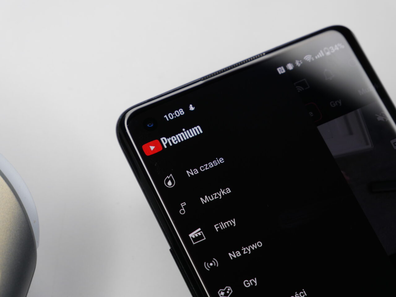 Smartfon wyświetlający interfejs aplikacji YouTube z akcentem na logo YouTube Premium, położony na białej powierzchni.