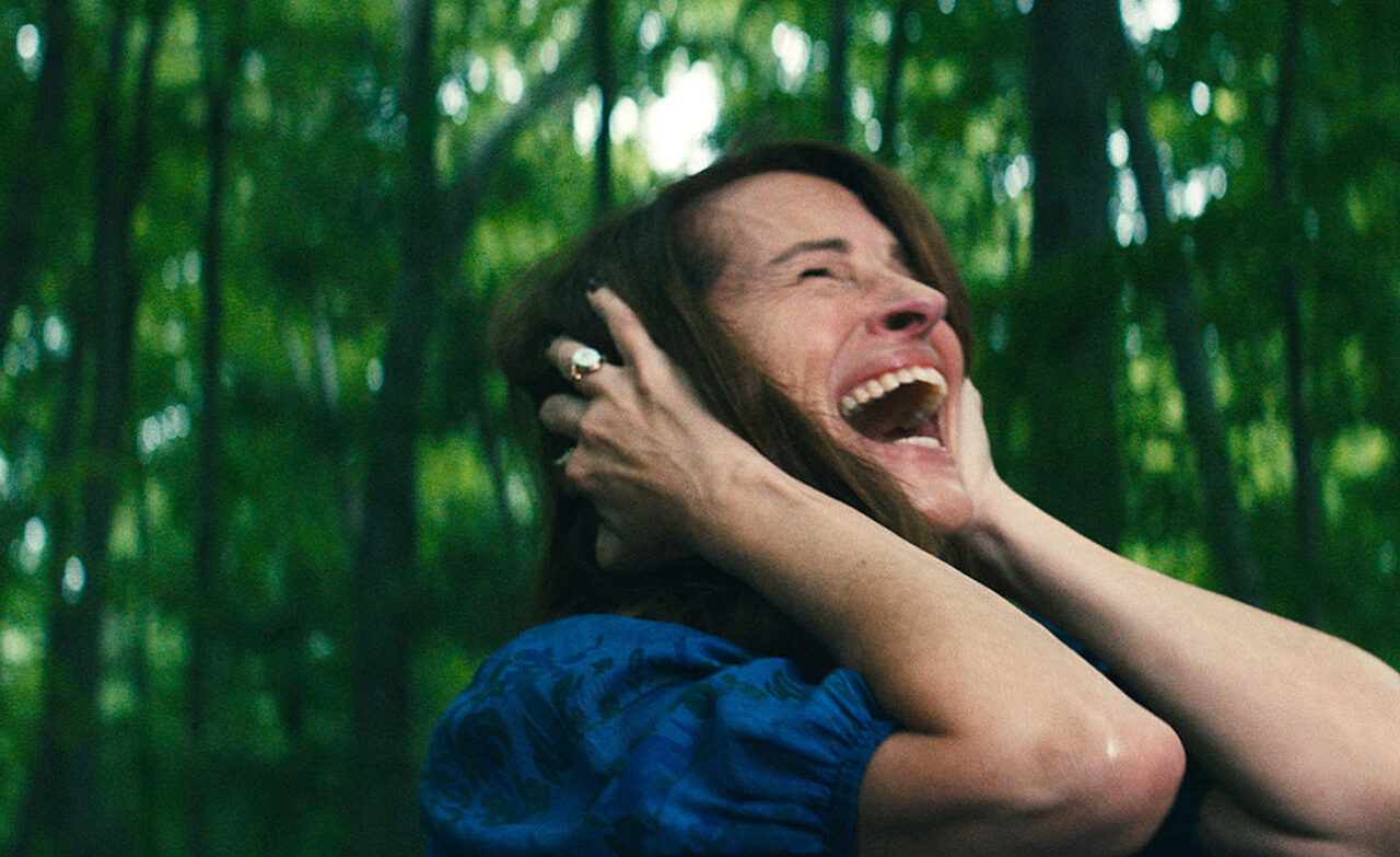 Kobieta krzycząca w lesie z rozmytym tłem.