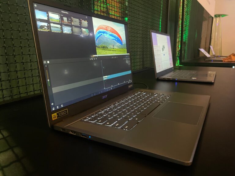Laptop Acer Chromebook na biurku z otwartym oprogramowaniem do edycji wideo, w tle inne komputery na ciemnym biurku oyświetlonym zielonym światłem LED.