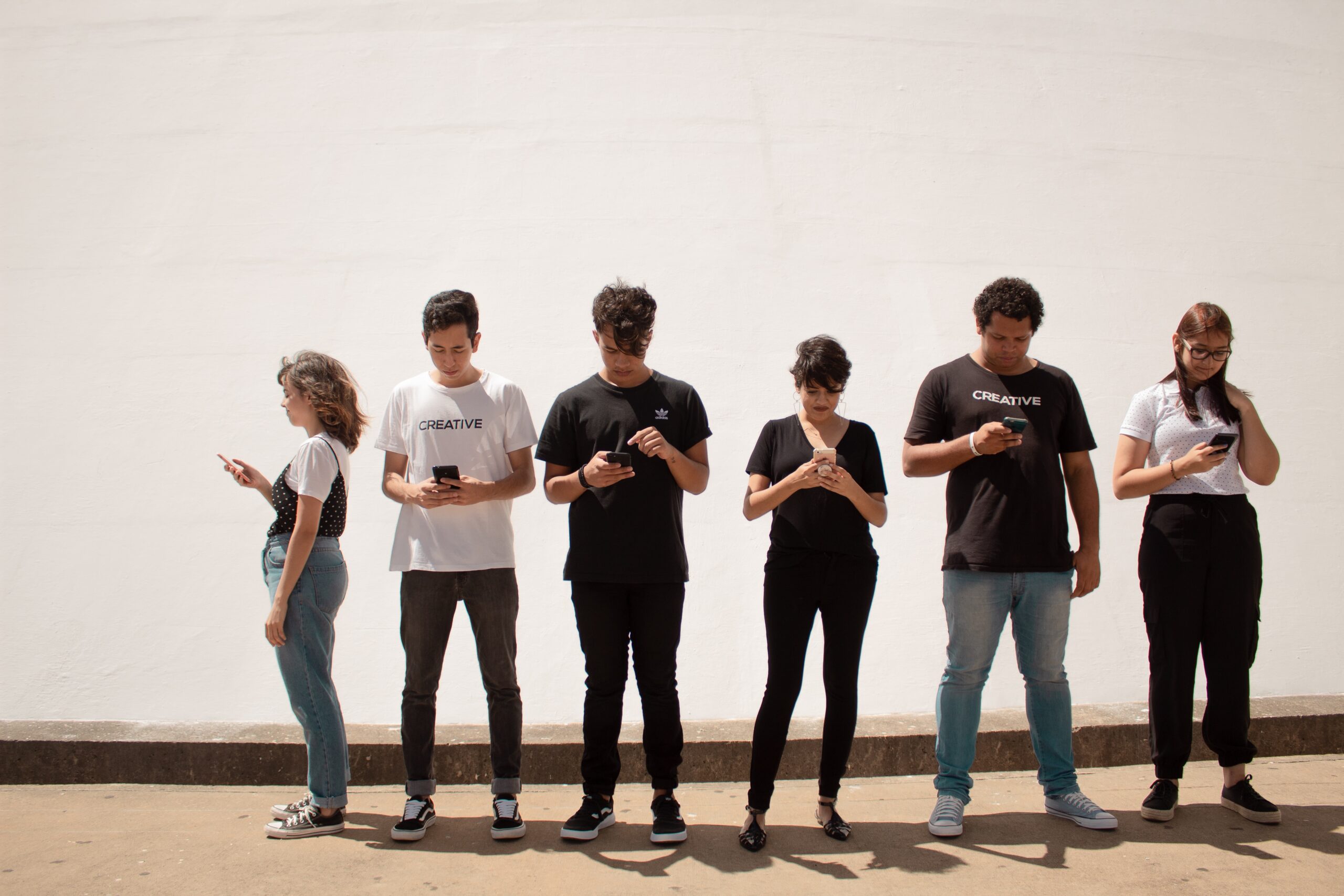 6 osób stojących, trzymających w rękach smartfony