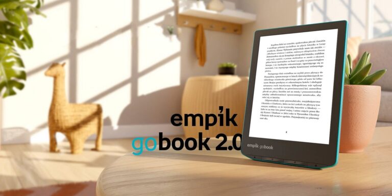 Czytnik e-booków Empik GoBook 2.0 na tle drewnianego biurka. Obok figurka lamy.