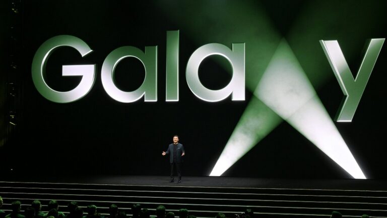 Mężczyzna prezentujący na scenie przed dużym, podświetlonym napisem "Galaxy".