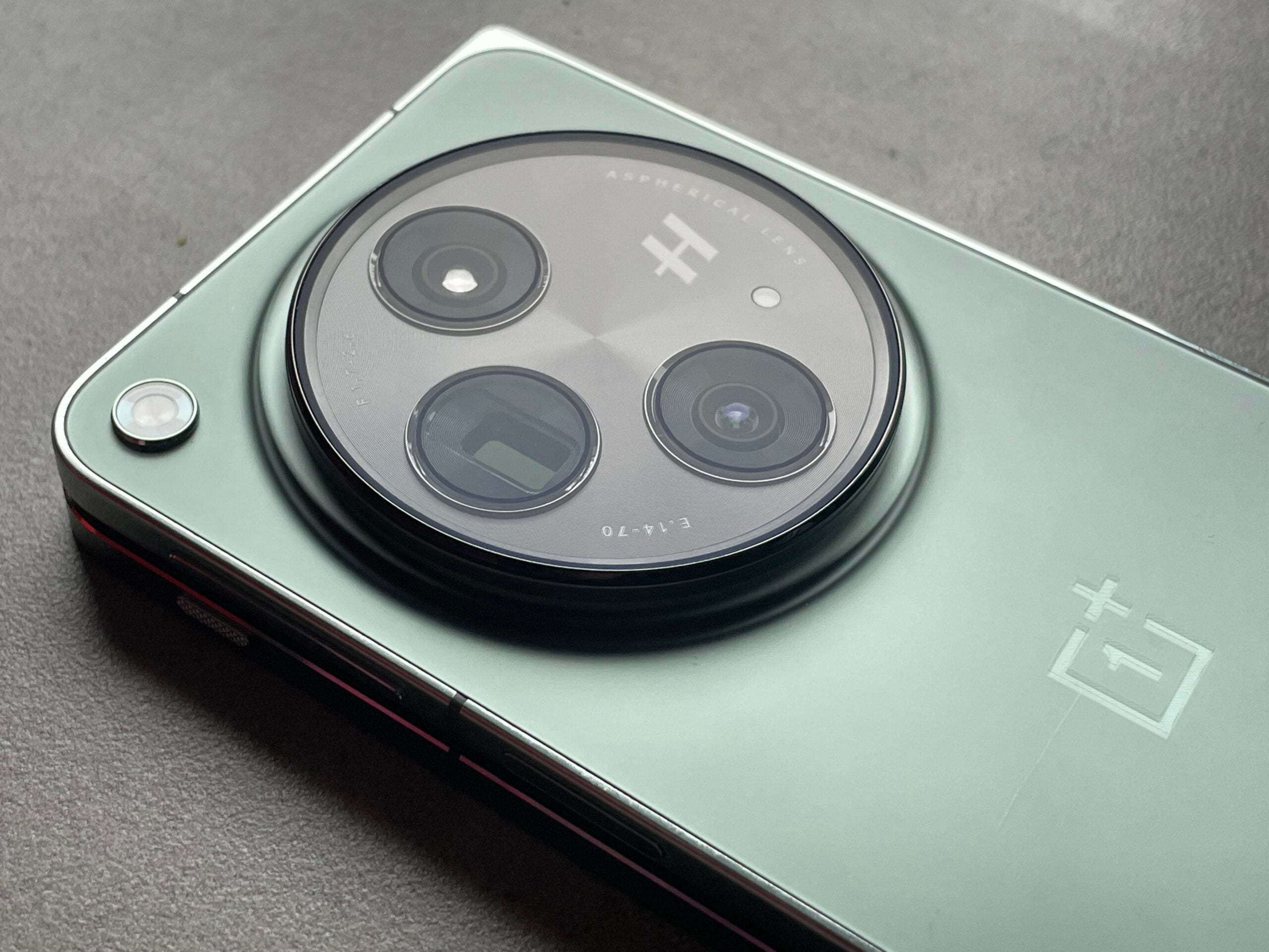 Smartfon w kolorze zielonym z widocznym modułem potrójnej kamery i logo producenta, czyli recenzja oneplus open
