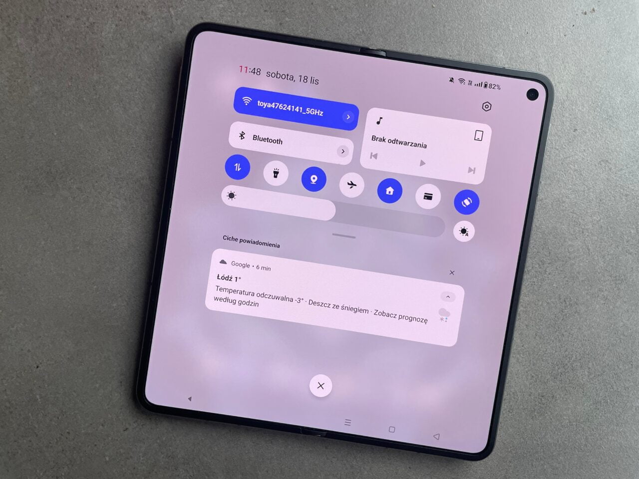 Tablet z otwartym menu szybkich ustawień i powiadomieniami, wyświetlającymi m.in. stan baterii, połączenia Wi-Fi, Bluetooth oraz pogodę. recenja oneplus open