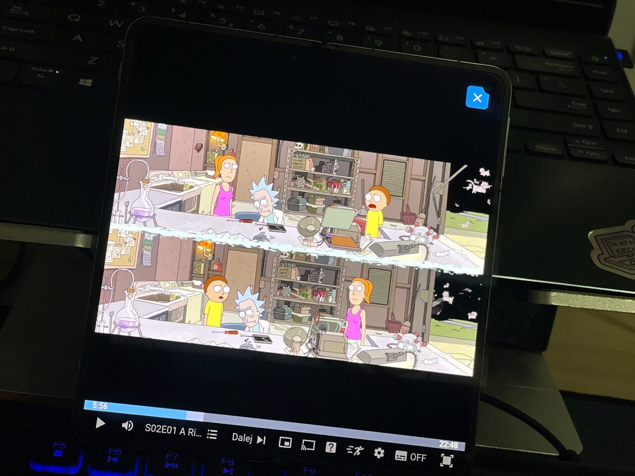 Tablet pokazujący scenę z animowanego serialu, stojący na klawiaturze laptopa. recenzja oneplus open