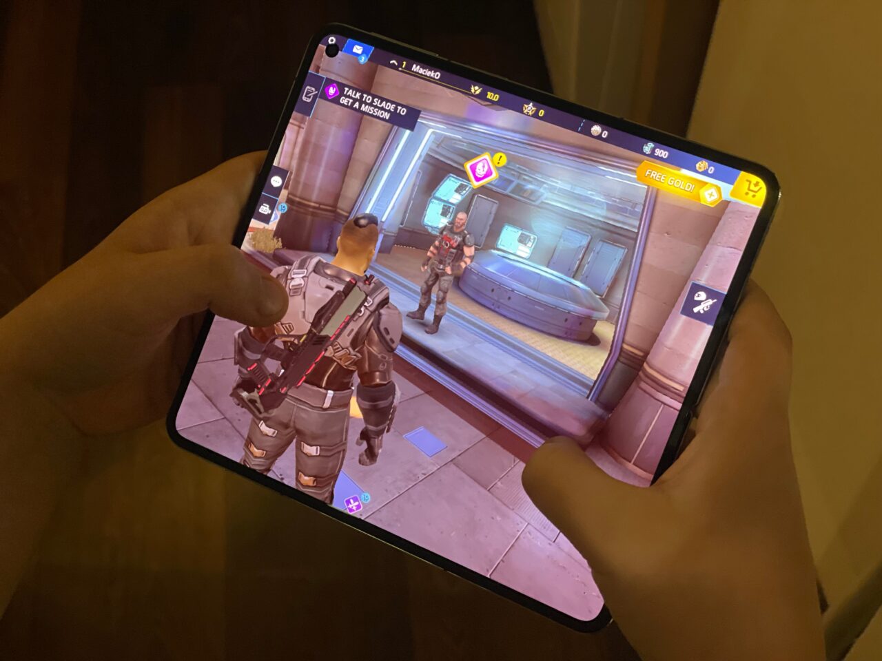 Ujęcie rąk trzymających tablet z wyświetlaną grą wideo, gdzie na ekranie widoczna jest postać w futurystycznym pancerzu oraz interfejs gry. recenzja oneplus open