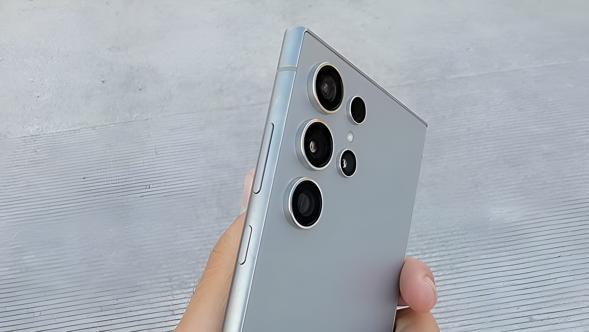 Samsung Galaxy S24 Ultra Osoba trzyma smartfona srebrnego koloru z potrójnym aparatem i przyciskami bocznymi widocznymi z tyłu urządzenia.