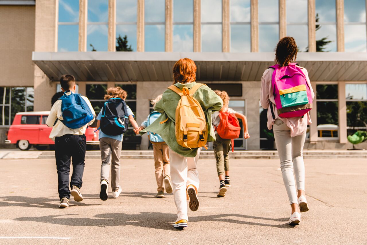 nvidia geforce back to school. Grupa dzieci z plecakami biegnąca w stronę budynku szkolnego.