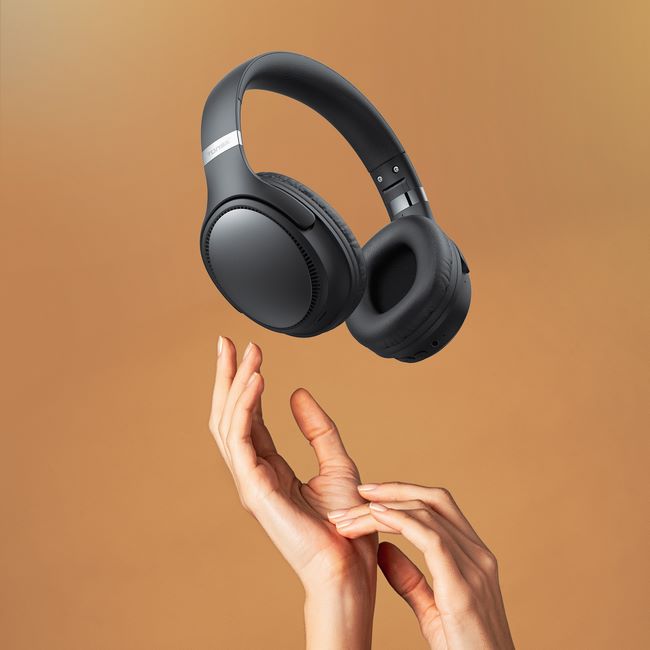 Słuchawki bezprzewodowe Tonsil na brązowym tle. Poniżej widoczne dłonie