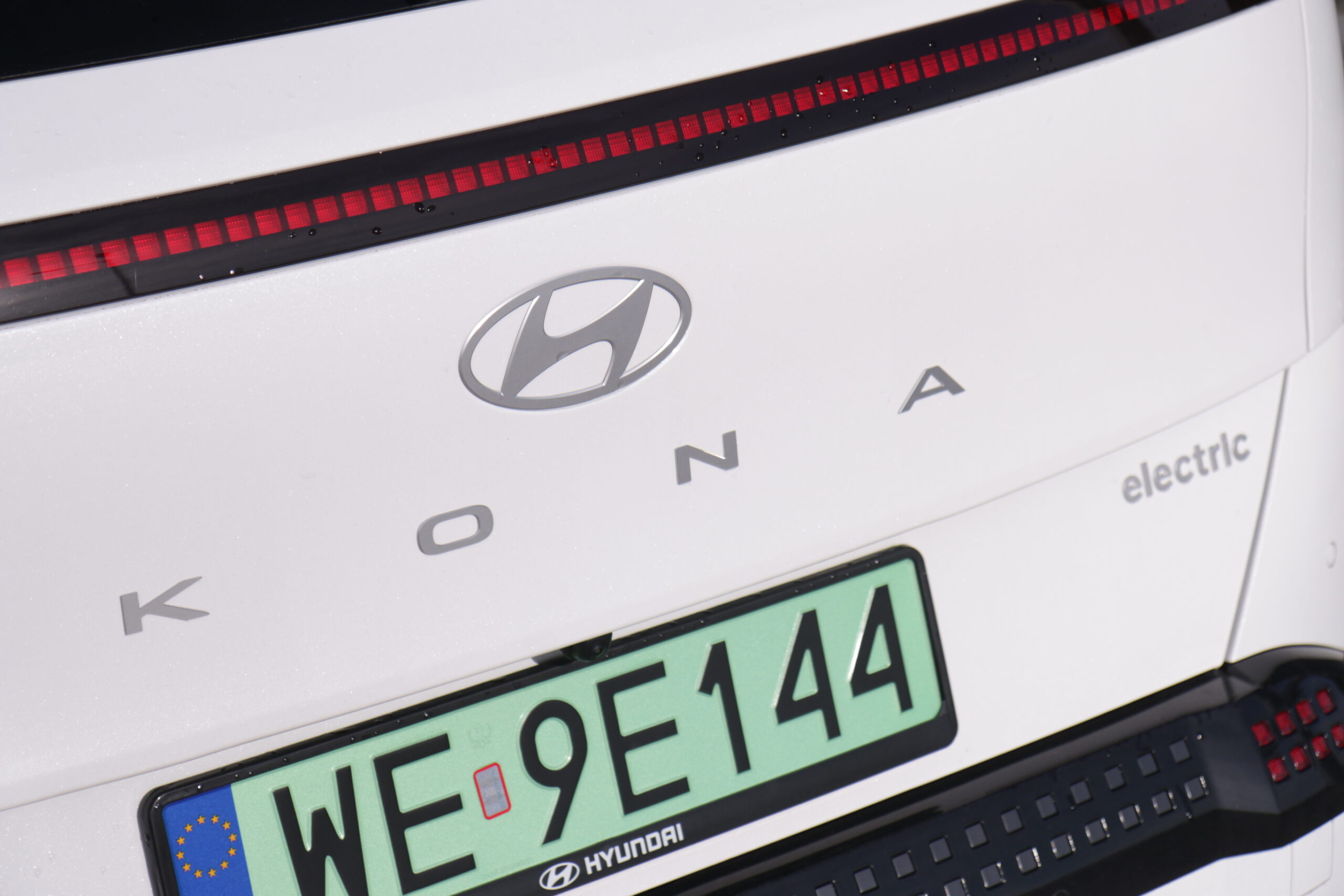 Testowany Hyundai Kona II Electric widoczny od tyłu ze zbliżeniem na loga i zieloną tablicę rejestracyjną.