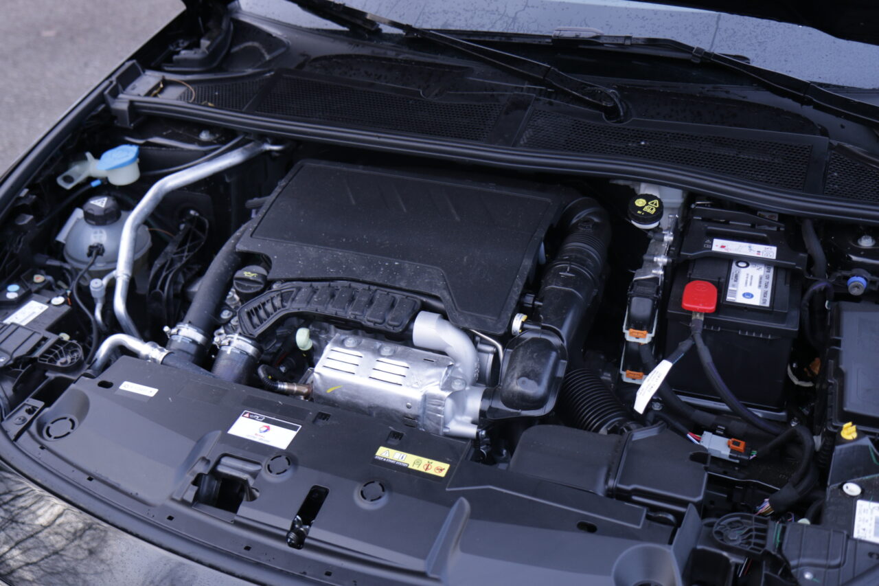 Podniesiona maska samochodu z widocznym silnikiem, akumulatorem oraz innymi komponentami pojazdu - testowany Peugeot 308 III w benzynie