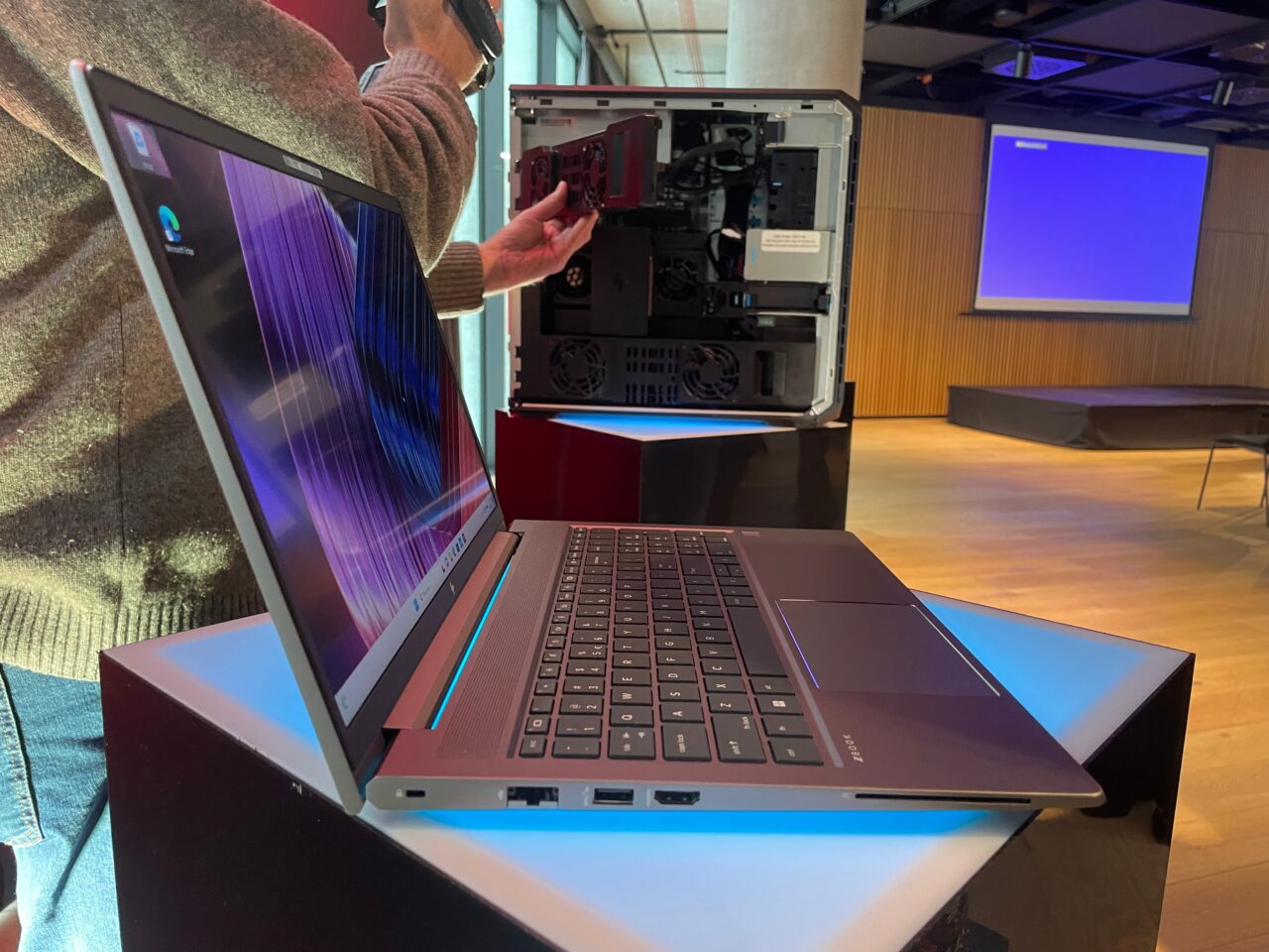 Otwarta obudowa komputera HP Z6 G5 A w tle, na pierwszym planie laptop na stole w pomieszczeniu konferencyjnym.