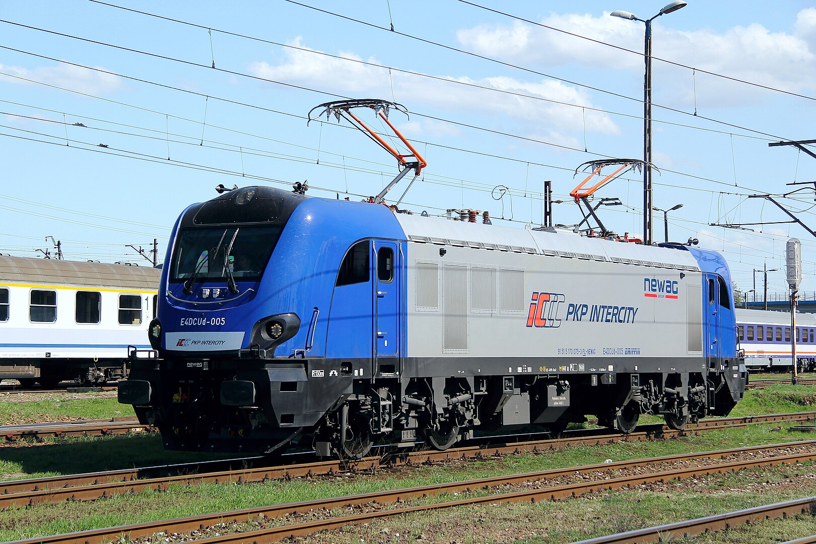 Niebiesko-szary lokomotywa PKP Intercity na torach z wyraźnym oznakowaniem.