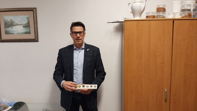 dr hab. inż. Tomasz Klepka, profesor Politechniki Lubelskiej w okularach i garniturze trzymający paletę z małymi próbkami materiału, które stworzyła maszyna do recyklingu