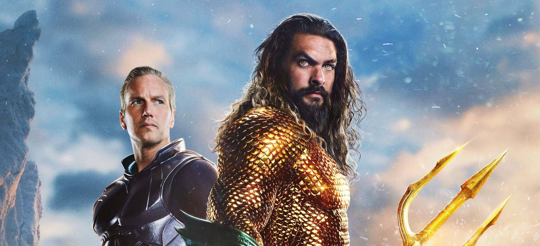 Dwóch mężczyzn w kostiumach superbohaterów, jeden z trójzębem, na tle dramatycznie oświetlonego nieba. Kadr z plakatu do filmu Aquaman i Zaginione Królestwo