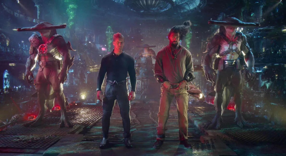 Czterej bohaterowie stoją na pierwszym planie w fantazyjnym, oświetlonym neonami mieście – dwóch ludzi i dwie postacie antropomorficzne ubrane w futurystyczne stroje. Zdjęcie do artykułu o recenzji filmu Aquaman i Zaginione Królestwo
