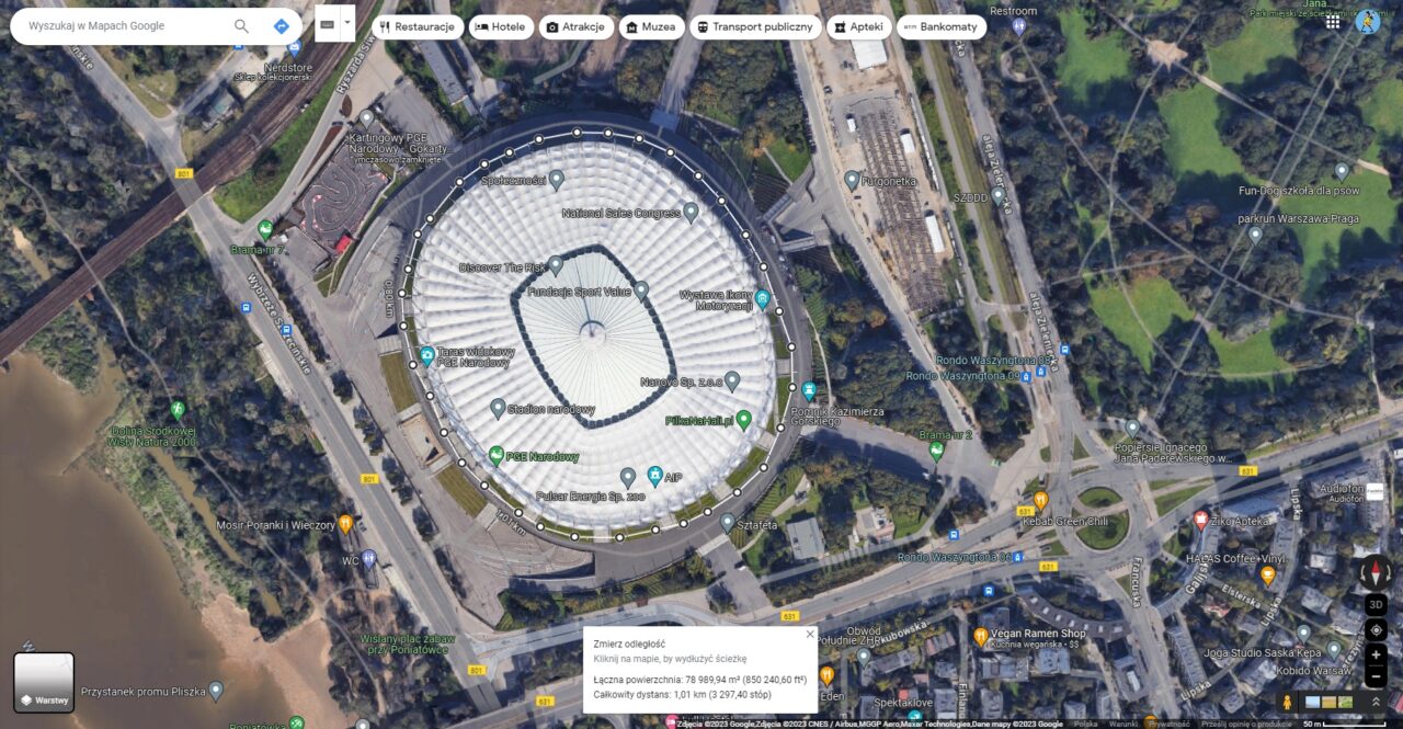 Zdjęcie satelitarne Stadionu Narodowego w Warszawie wraz z otaczającym go infrastrukturą i terenami zielonymi.
