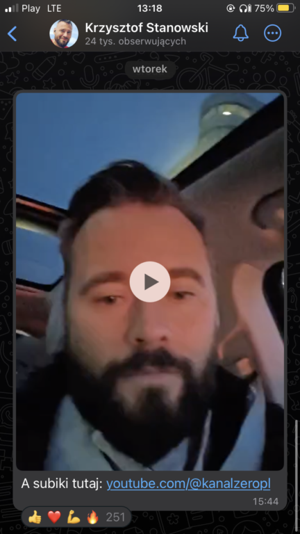 Screen aplikacji społecznościowej z podglądem filmu przedstawiającego mężczyznę z brodą w samochodzie, z ikoną odtwarzania na środku. Na ekranie Krzysztof Stanowski