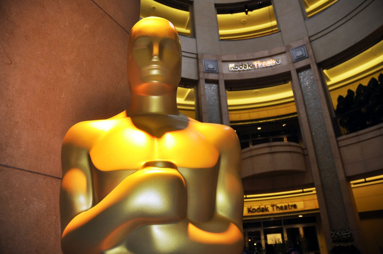 Duża, złota statua Oscara z widocznym napisem "Kodak Theatre" w tle. Zdjęcie pokazujące Dolby Theatre gdzie odbędą się Oscary 2024