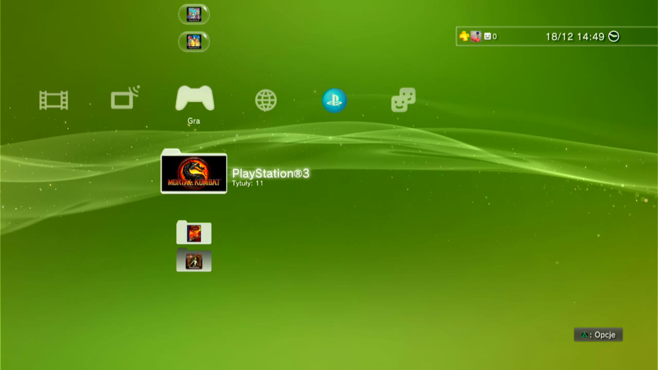 Ekran menu konsoli PlayStation 3 z ikonami gier, w tym Mortal Kombat, na zielonym tle w dynamicznym stylu z ozdobnymi liniami i iskierkami. Aktualizacja PlayStation 3 nie zmieniła wyglądu interfejsu