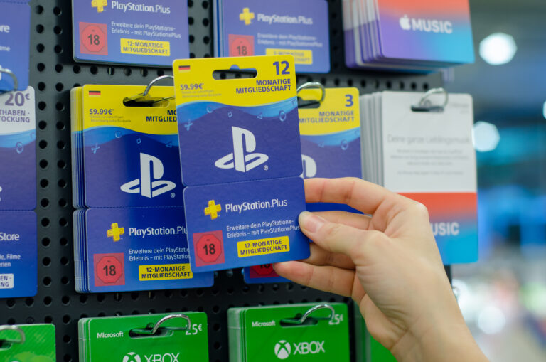 Karta podarunkowa PlayStation Plus na 12 miesięcy jest wyjmowana z wystawki w sklepie z elektroniką.
