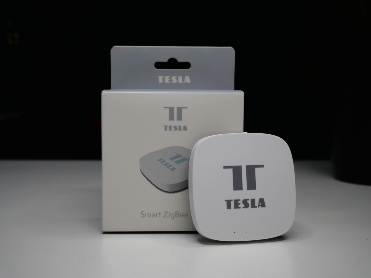 Stacja centralna firmy Tesla oznaczony logo "T" z opakowaniem na ciemnym tle.