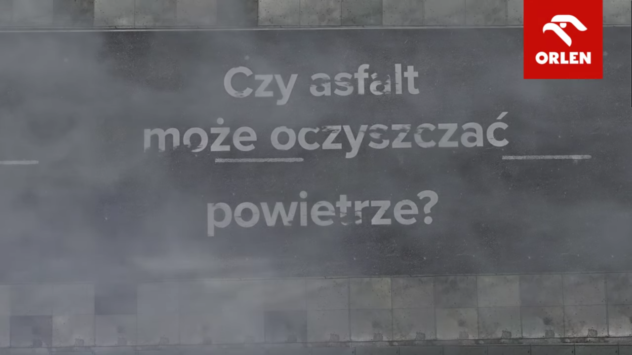 Zrzut ekranu z filmu video prezentujący pytanie "Czy asfalt może oczyszczać powietrze?" i dodający "Testujemy ekologiczny wynalazek!" z logo firmy ORLEN w prawym górnym rogu mówiący o produkcie jakim jest ekologiczny asfalt