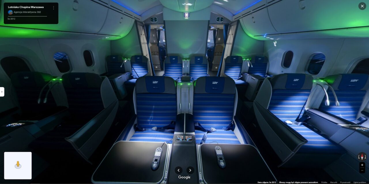 Wnętrze samolotu pasażerskiego z niebieskimi fotelami ustawionymi w konfiguracji 2-2, oświetlenie ambientowe w odcieniach zielonym i niebieskim, bez widocznych pasażerów.