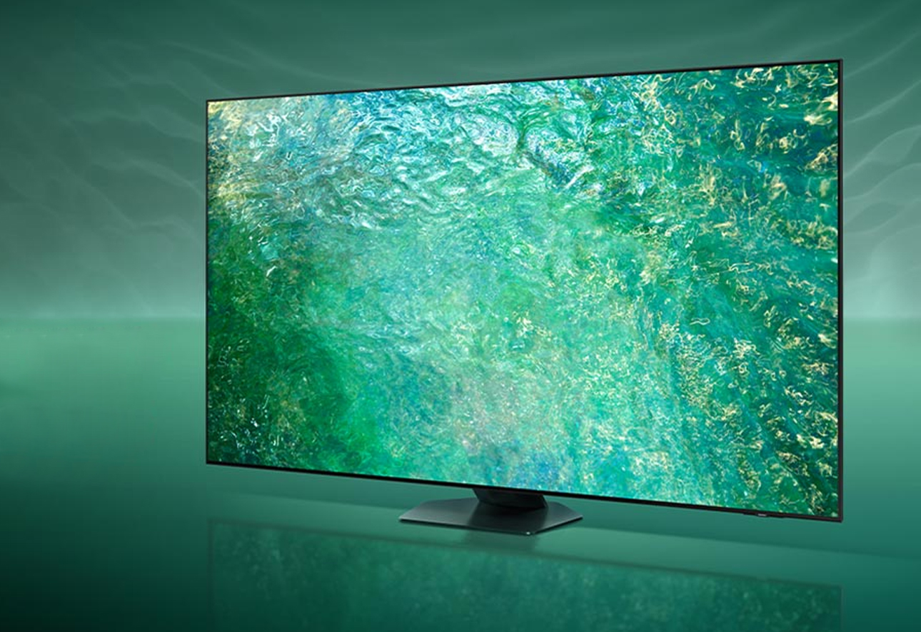 Telewizor na stojaku wyświetlający obraz krystalicznie czystej wody, umieszczony w pomieszczeniu z zielonym oświetleniem.